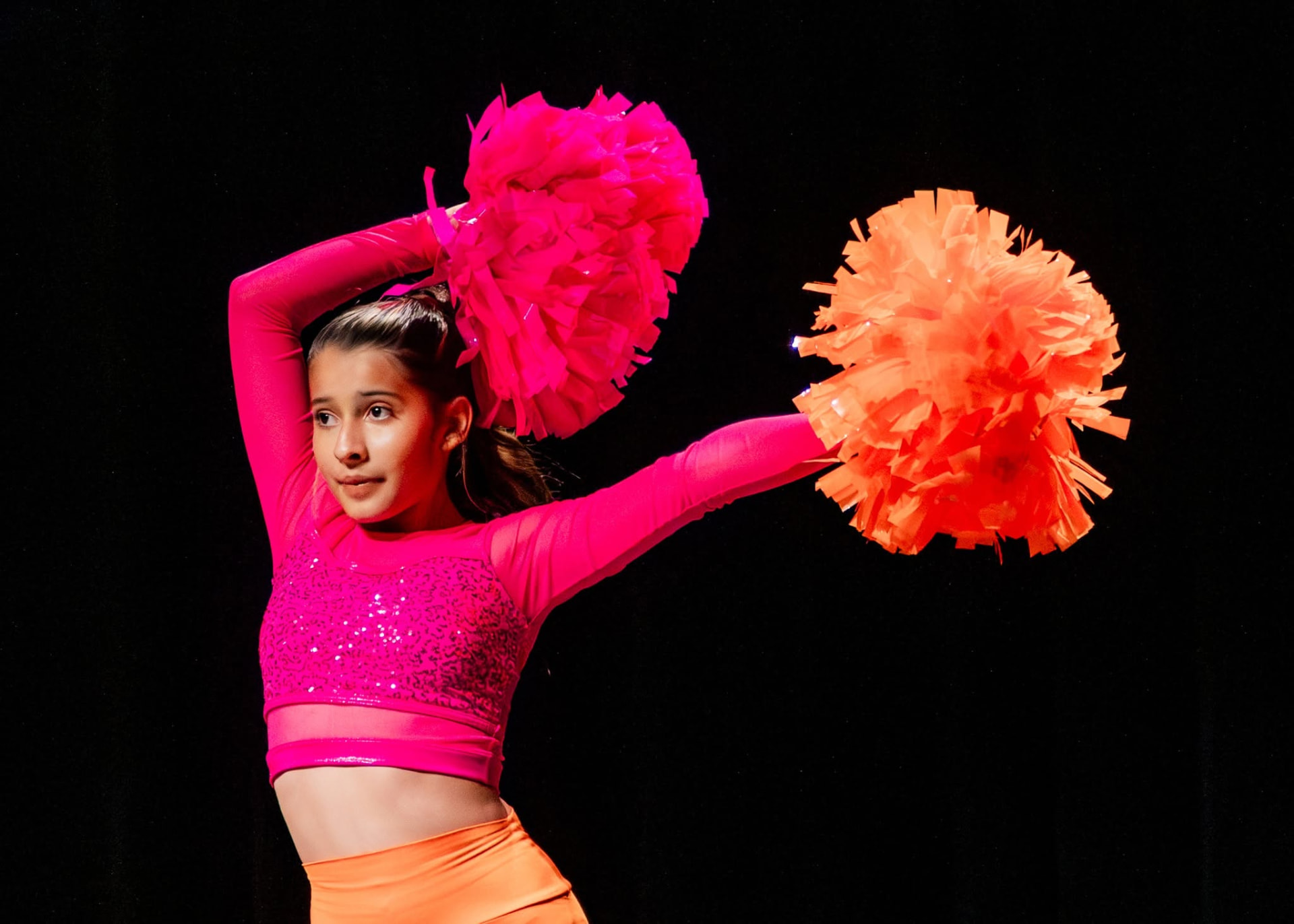 Pom dancer posing with pink and orange poms