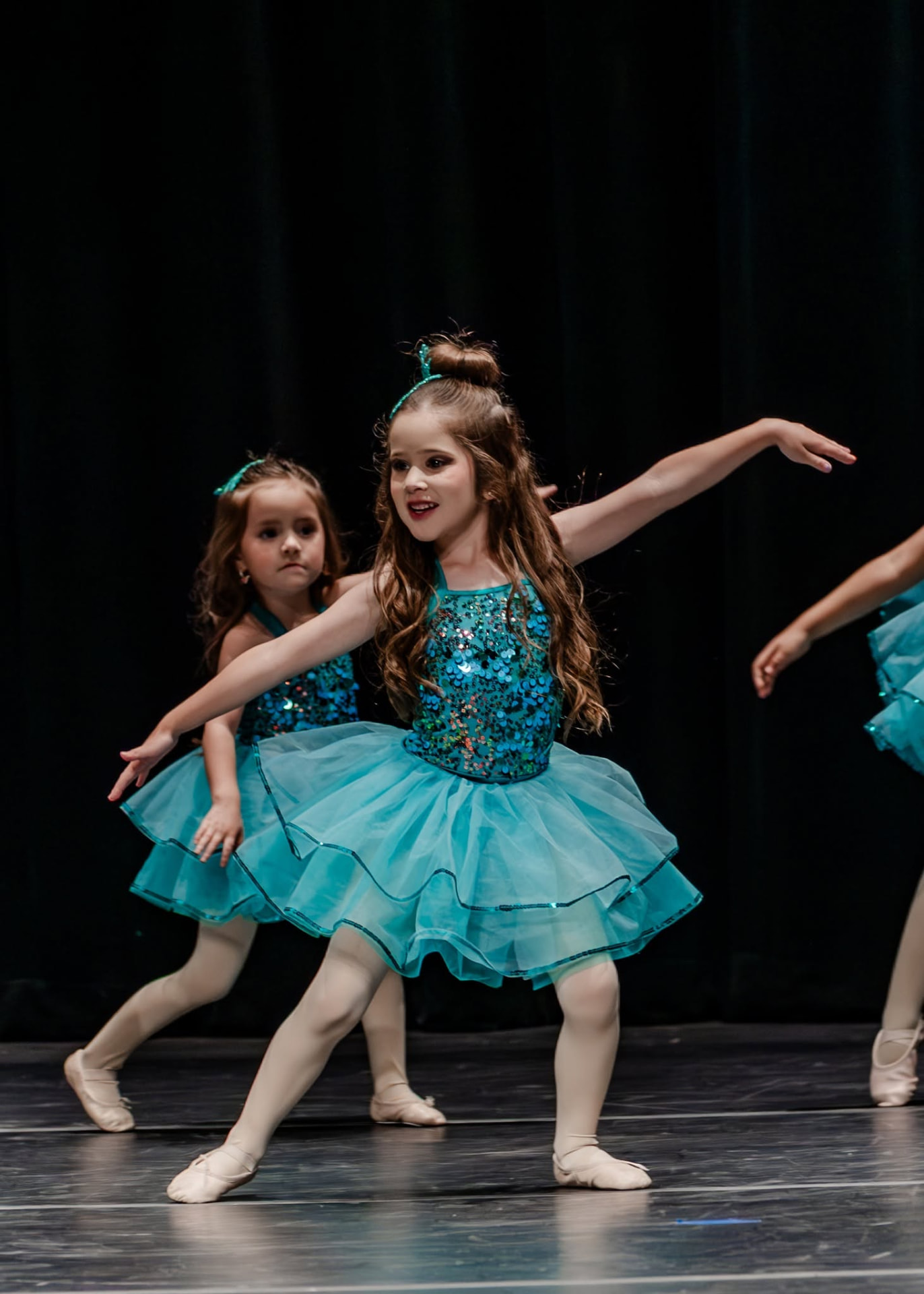Ballerinas in teal tutus in a wide second position