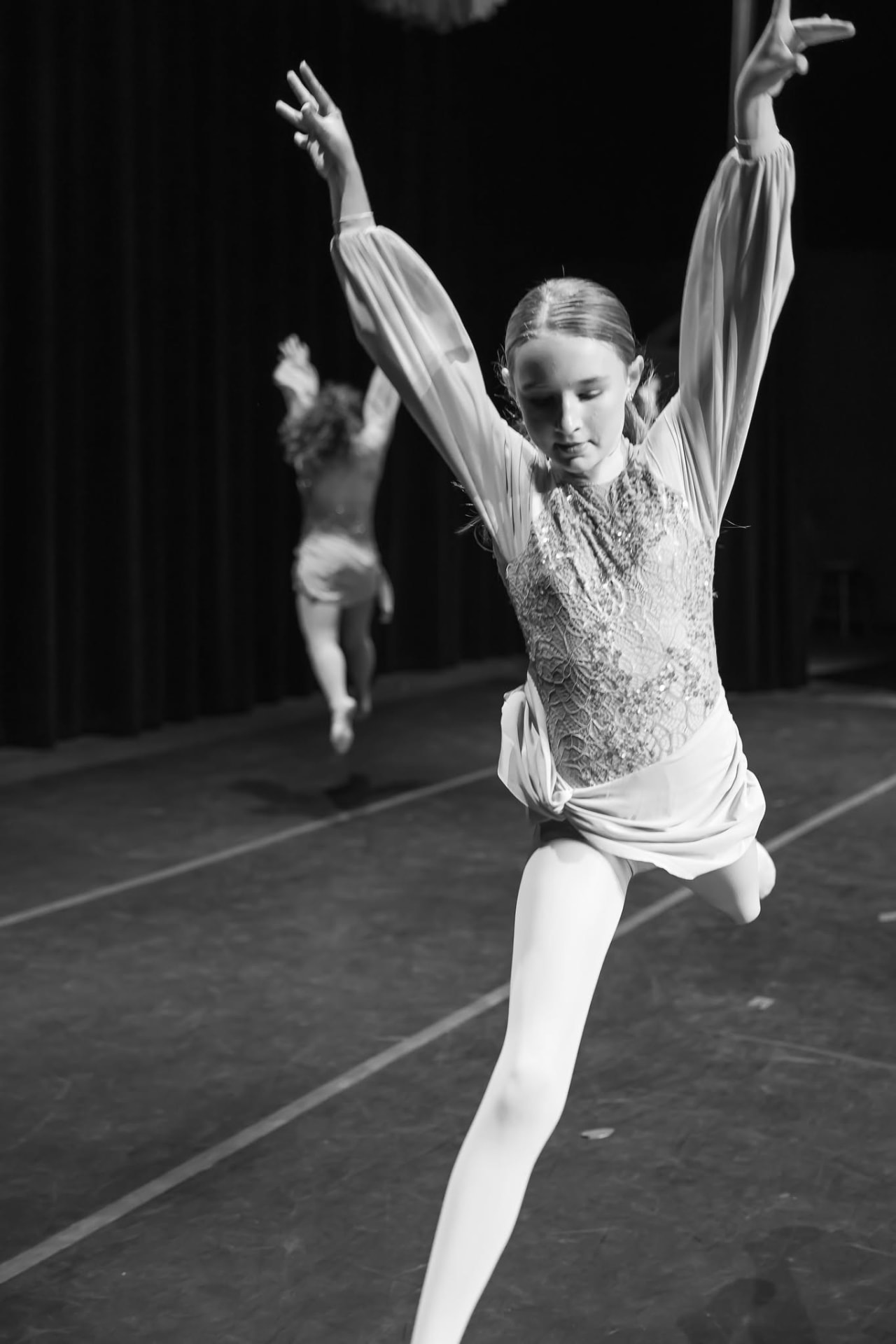 Dancer in a lace costume leaping with arms lifted