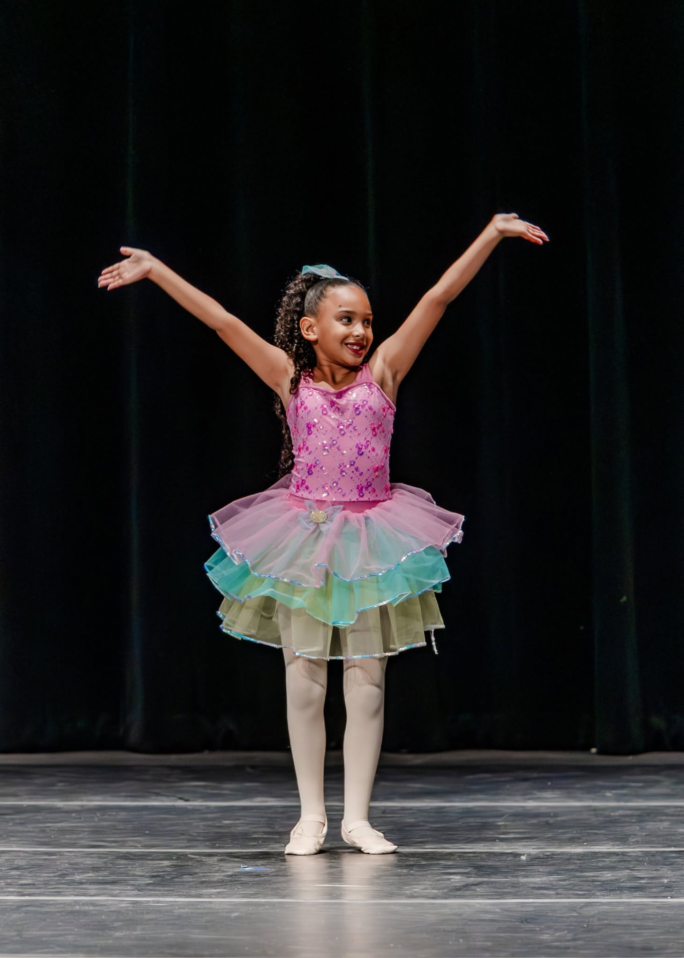 Ballerina in a pink and pastel tutu with arms open wide