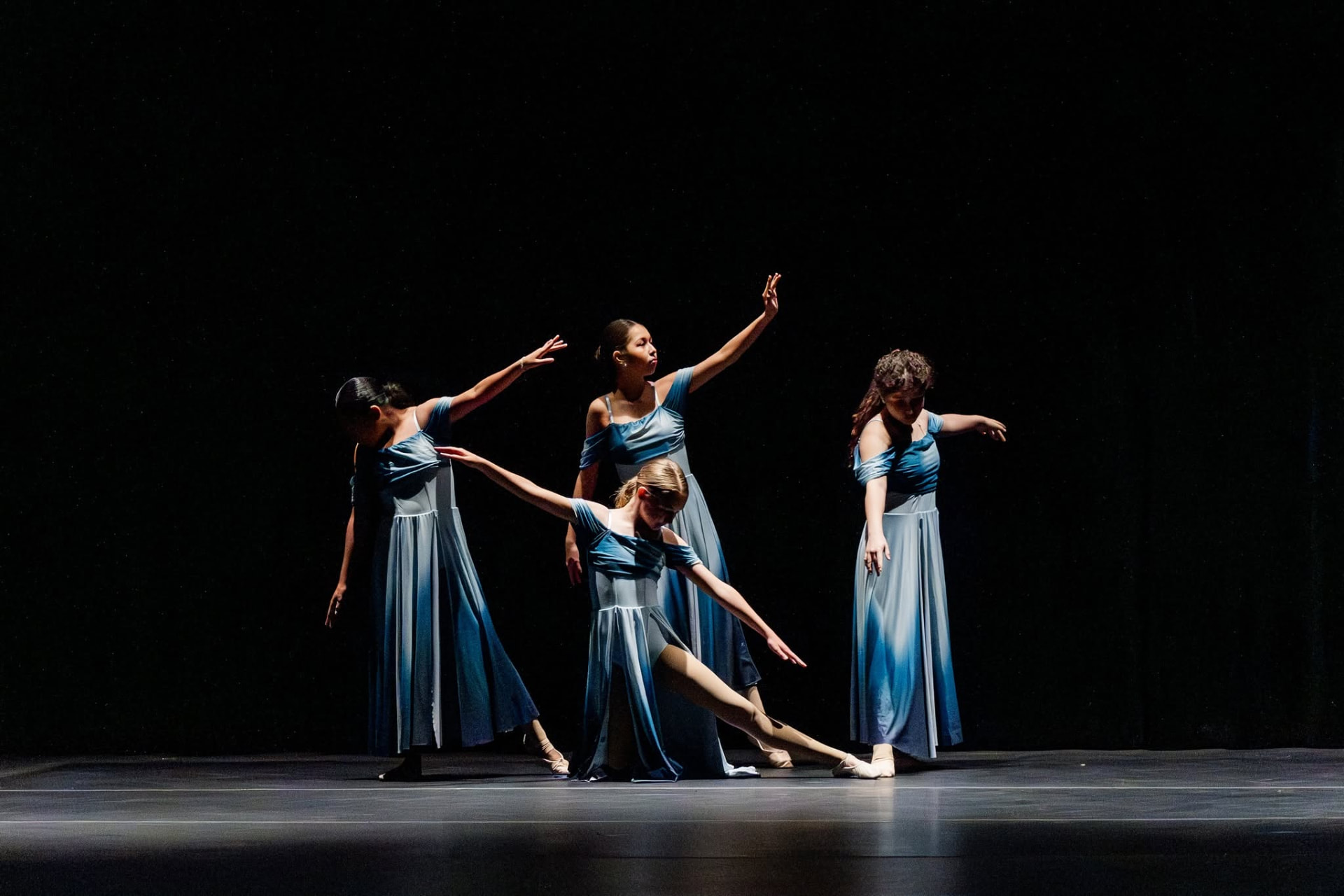 Four dancers in blue gowns in a lyrical group formation