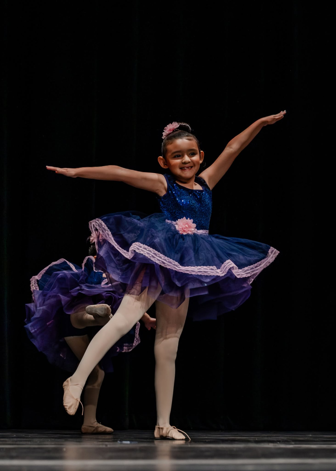 Young ballerina in a navy tutu balancing in passé