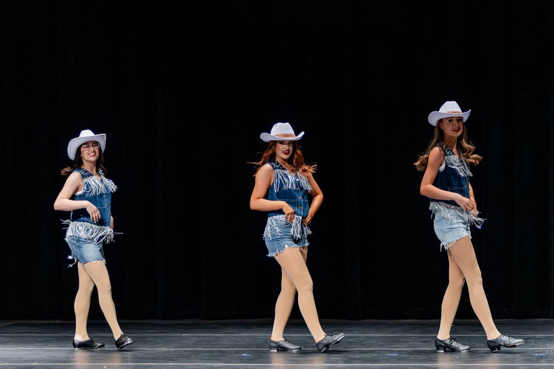 Three tap dancers in denim and white cowboy hats