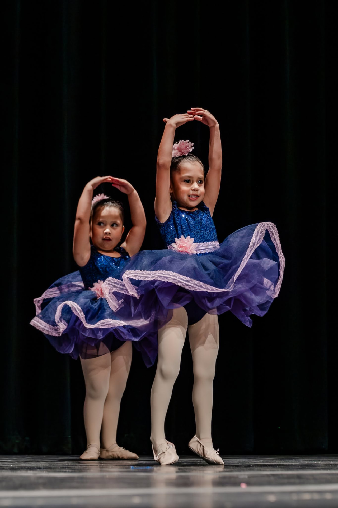 Two young ballerinas in navy and purple tutus in fifth position