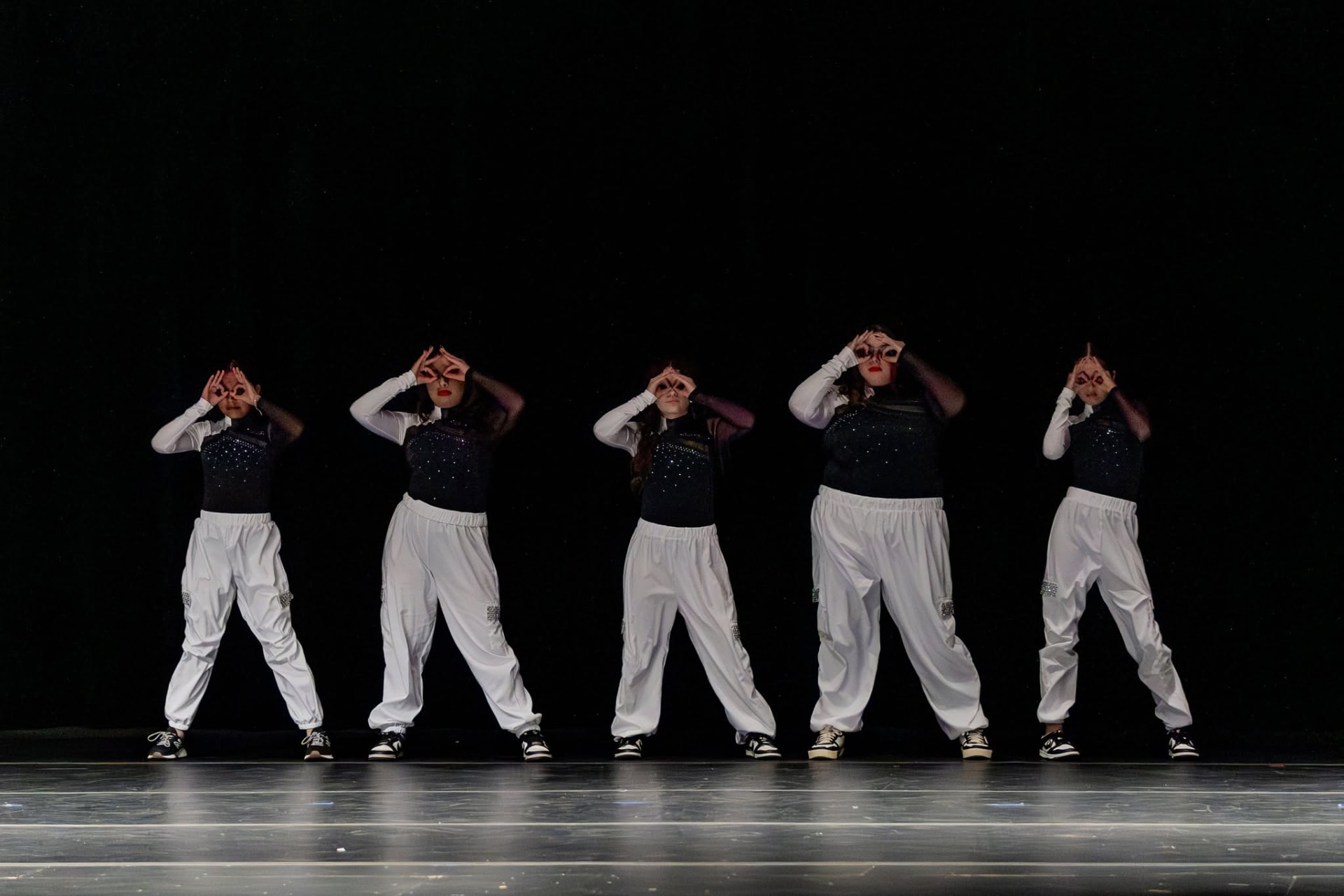 Five hip hop dancers in white pants in a synchronized line