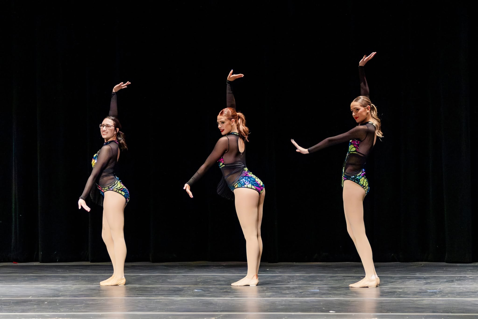 Three dancers in sequin leotards posing in profile
