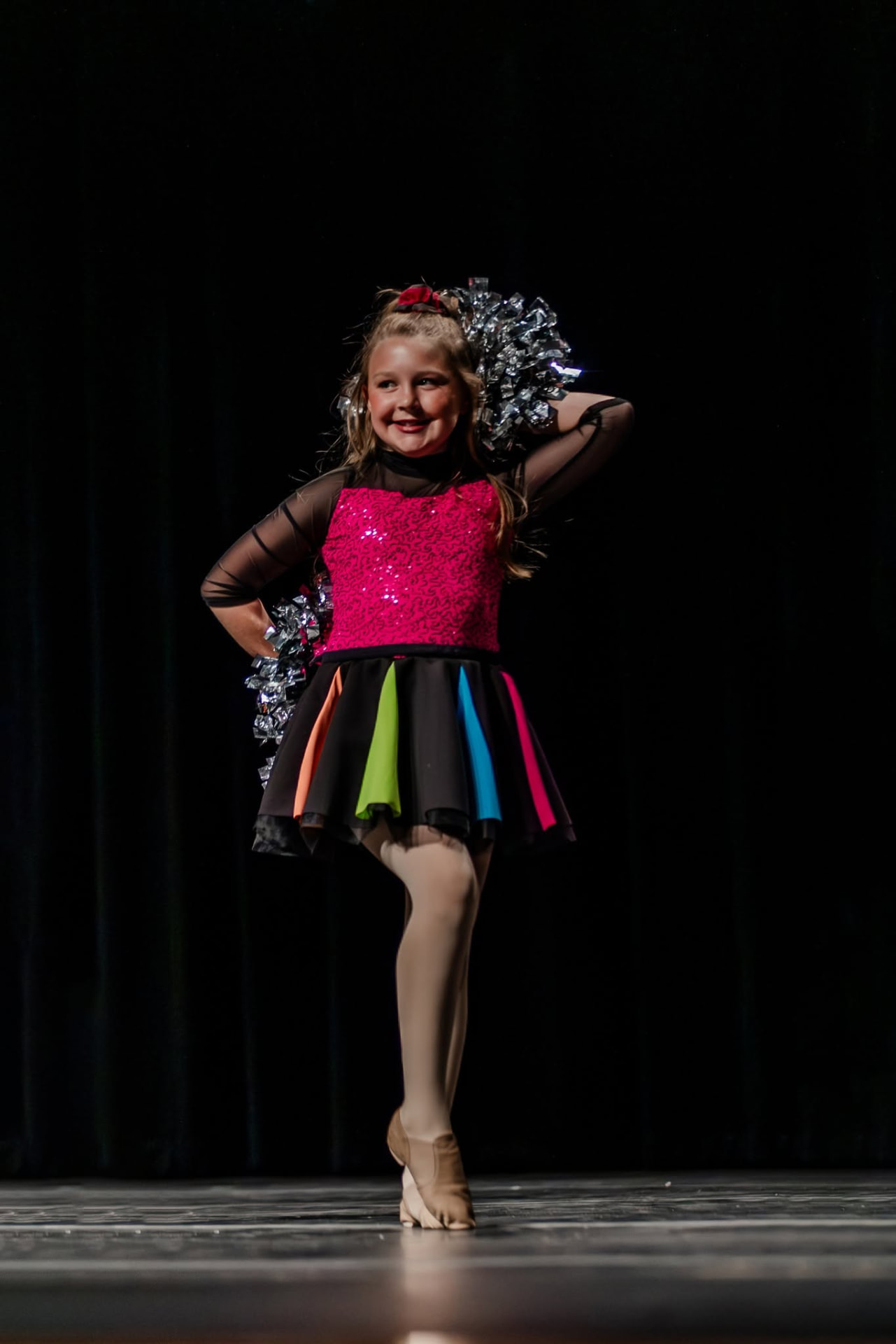 Pom dancer posing with silver poms in a bright costume