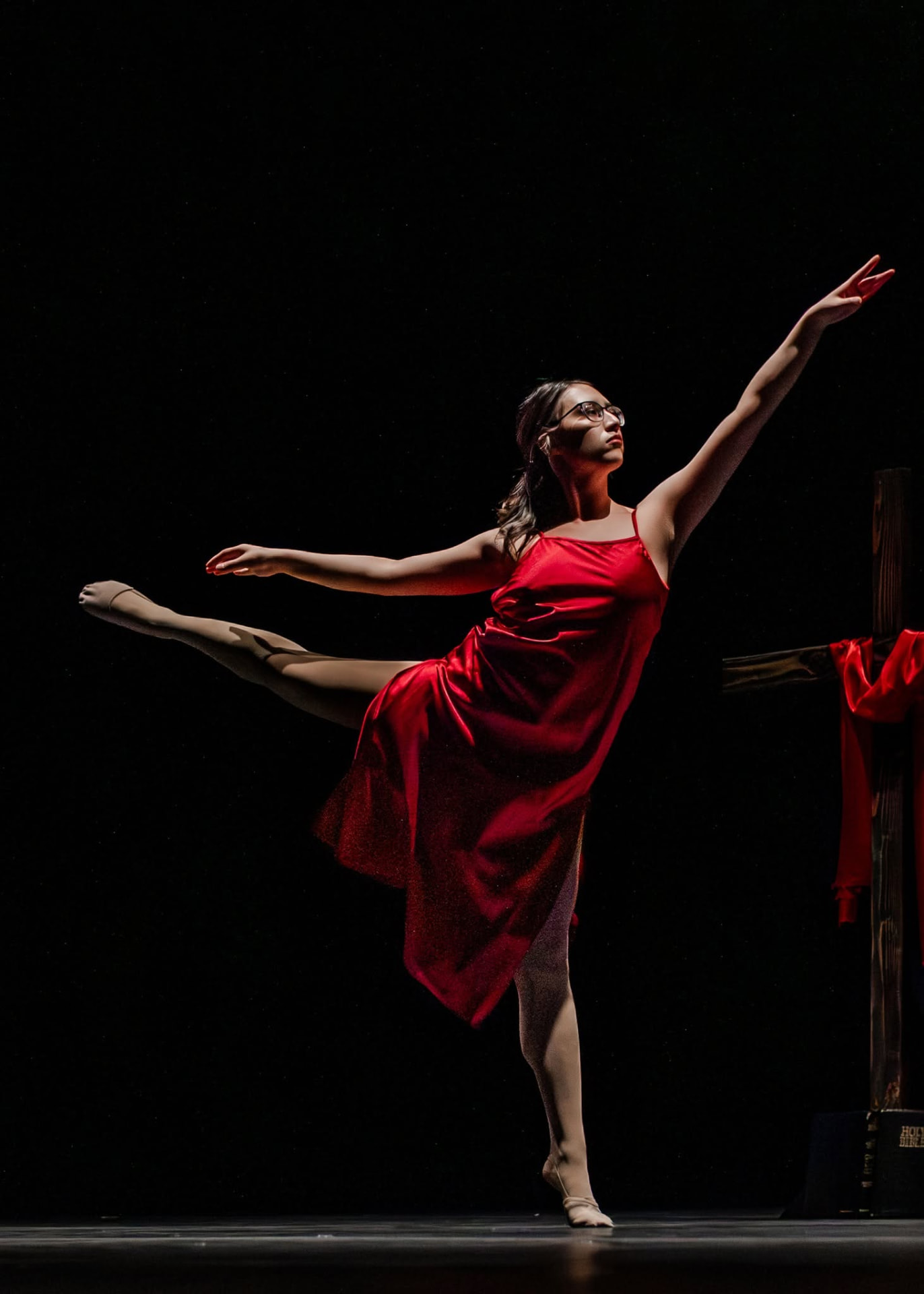 Soloist in a red dress in arabesque on stage