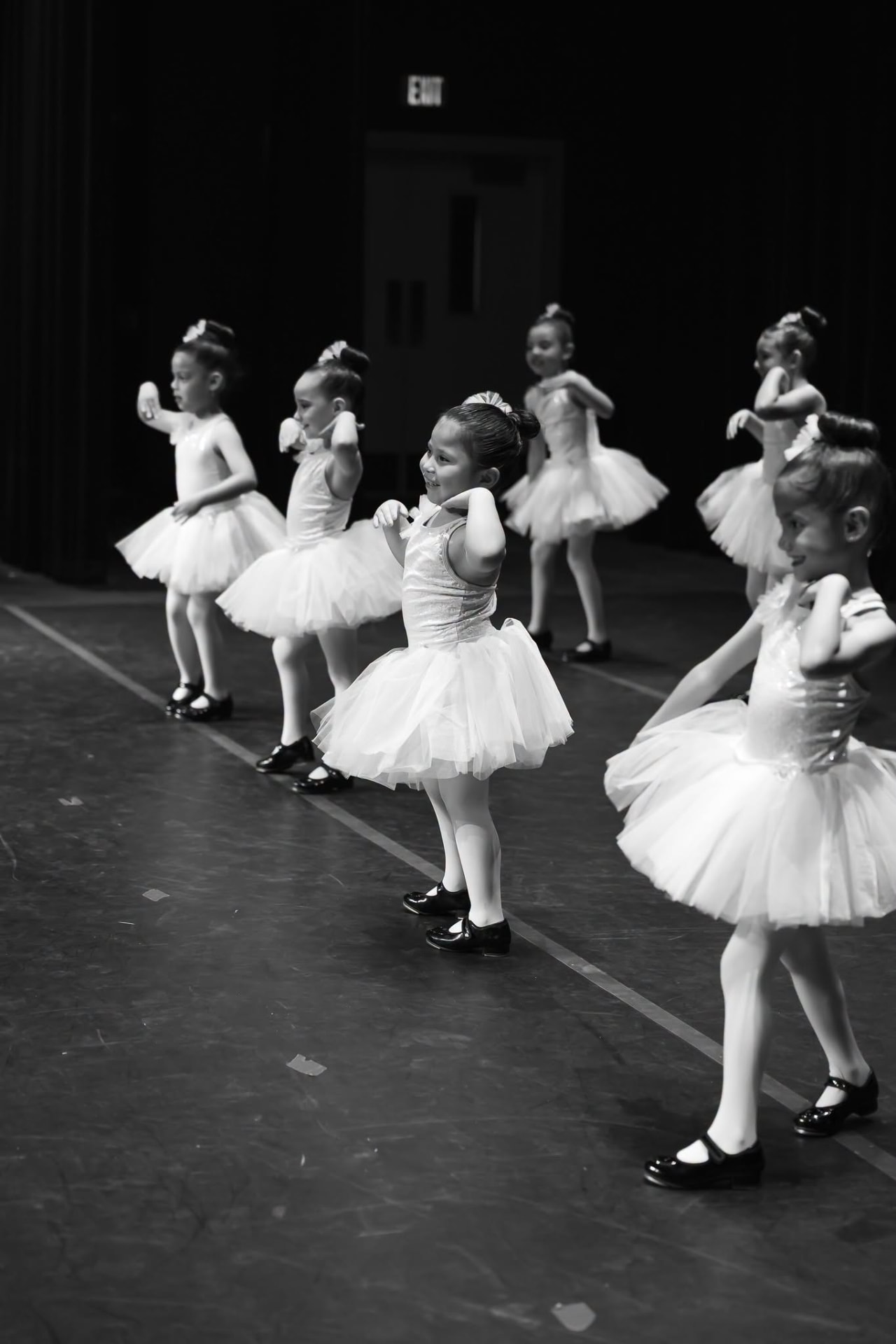 Line of young ballerinas in white tutus posing on stage