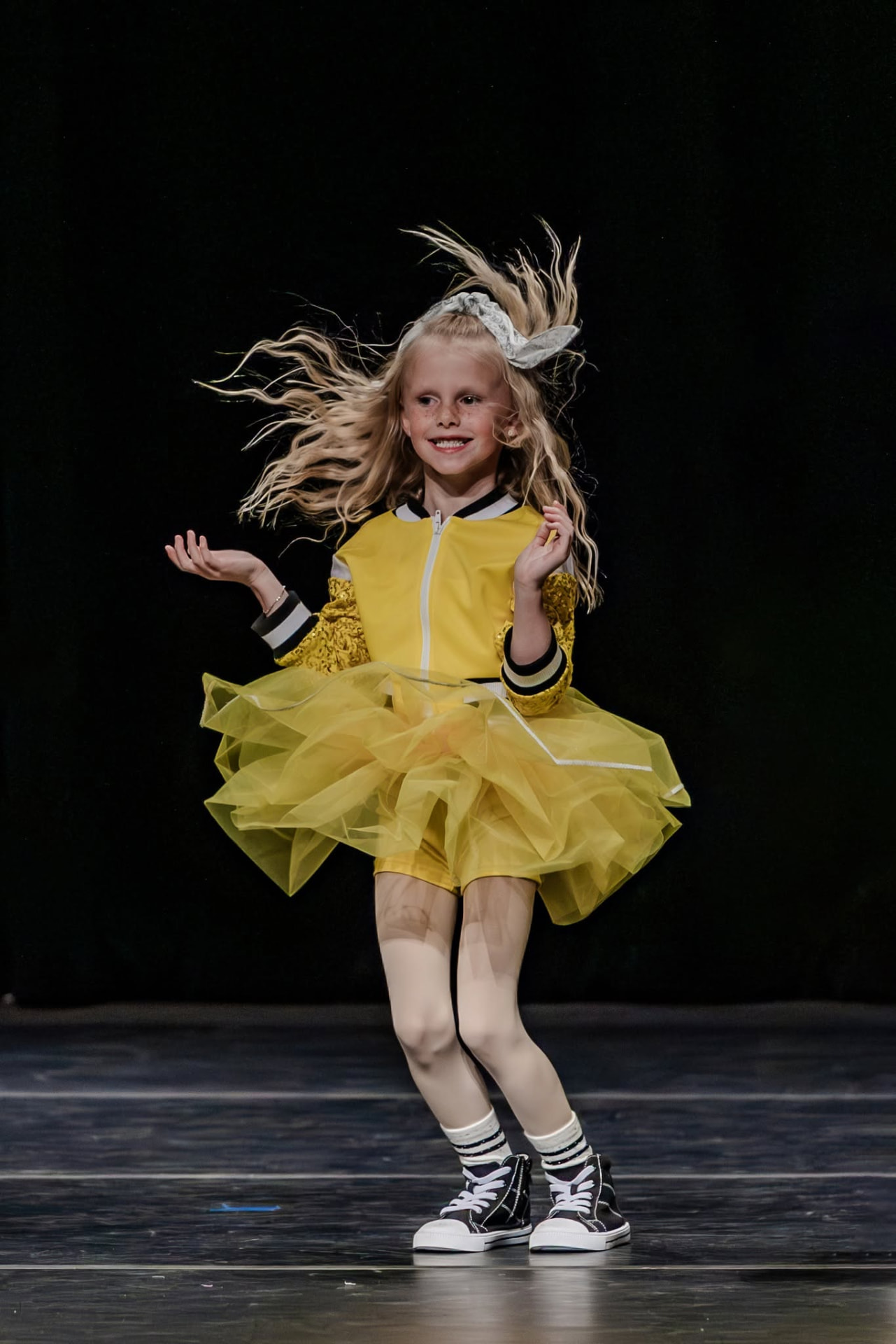 Young dancer in a yellow tulle costume with hair flying