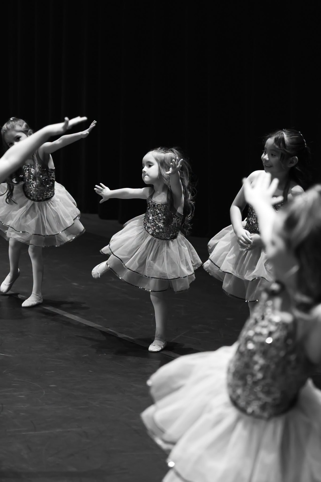 Tiny dancers in sequin tutus reaching out during their routine